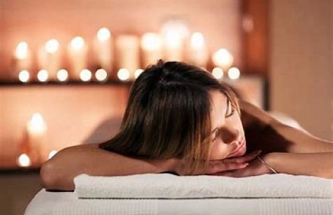 Una ragazza giace su un lettino da massaggio a lume di candela